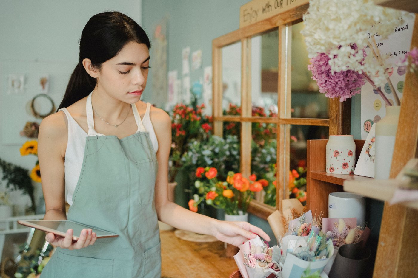 A small business owner checking orders on a tablet in her shop