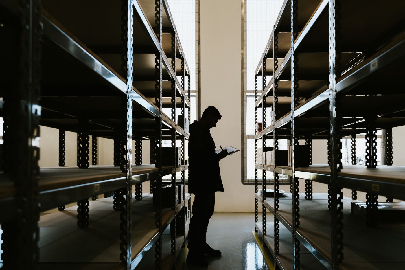 A warehouse worker checking delivered stock against a clipboard